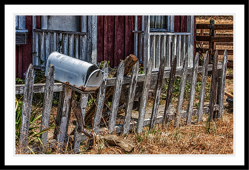 A mailbox sits on an old fence.